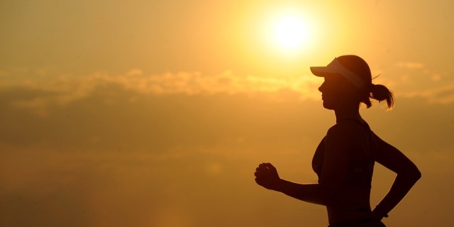 Mujer practicando running con el sol de fondo.
